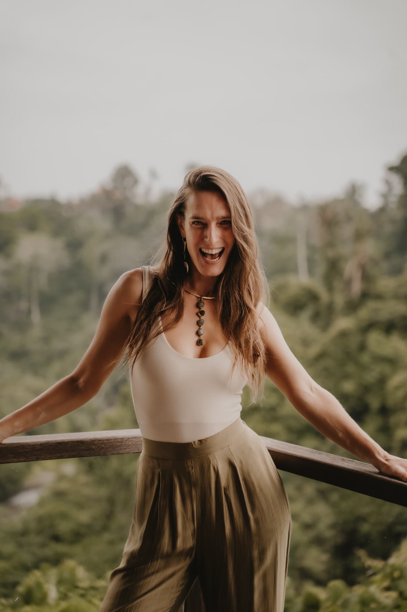 Arja Hendrikx laughing out loud on a balcony above the Bali jungle, arms wide on the railing