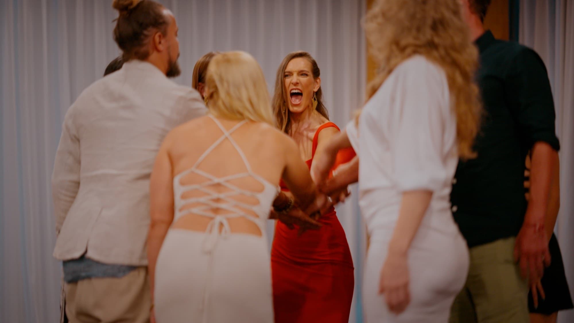 Arja Hendrikx in a red dress laughing out loud as a group stacks their hands together in a circle